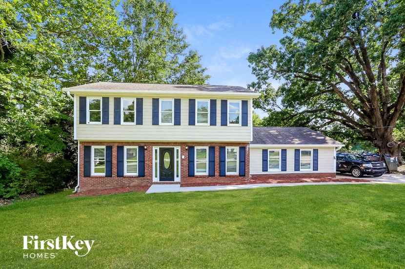 a white house with blue shutters and a green lawn