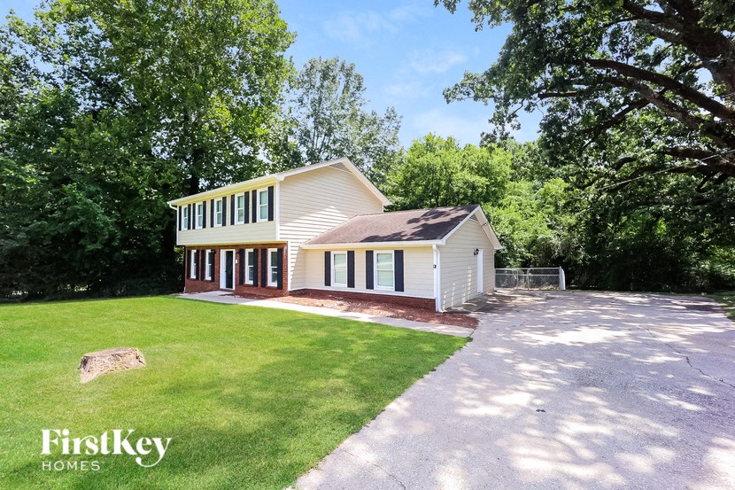 a white house with a driveway and a lawn and trees