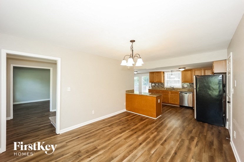 a kitchen and living room with wood flooring and a black refrigerator