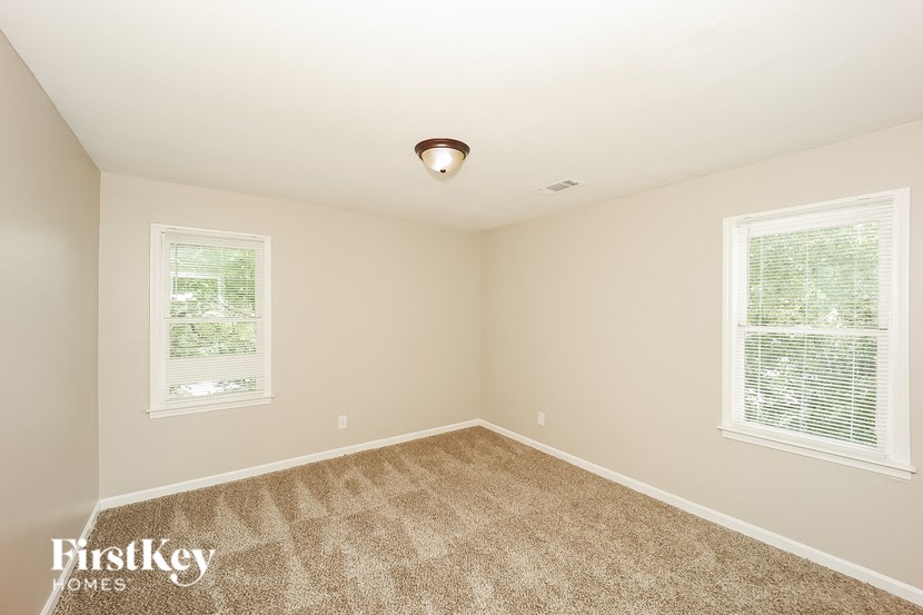 a bedroom with carpet and two windows
