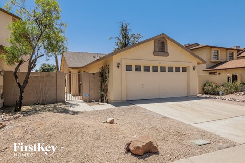 A house with a garage and a tree in front of it.