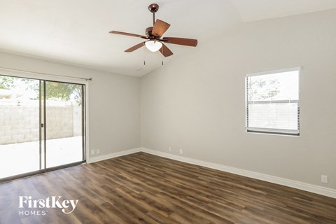A room with a ceiling fan and sliding glass doors.