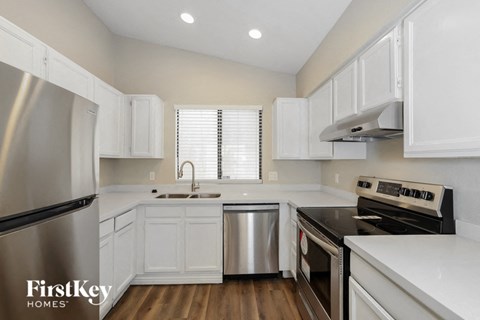 A kitchen with white cabinets and a stainless steel refrigerator.