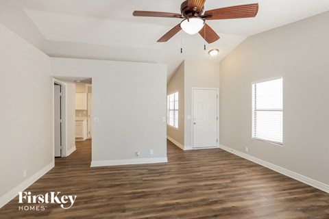 A spacious room with a ceiling fan and wooden flooring.
