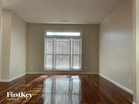 an empty living room with wood floors and a window