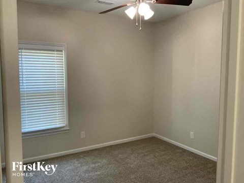 an empty bedroom with a ceiling fan and a window
