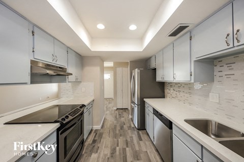 A kitchen with a stove top oven, a refrigerator, and a sink.