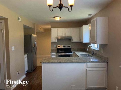 A kitchen with a granite countertop and white cabinets.