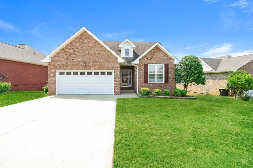 a large brick house with a white driveway and lawn
