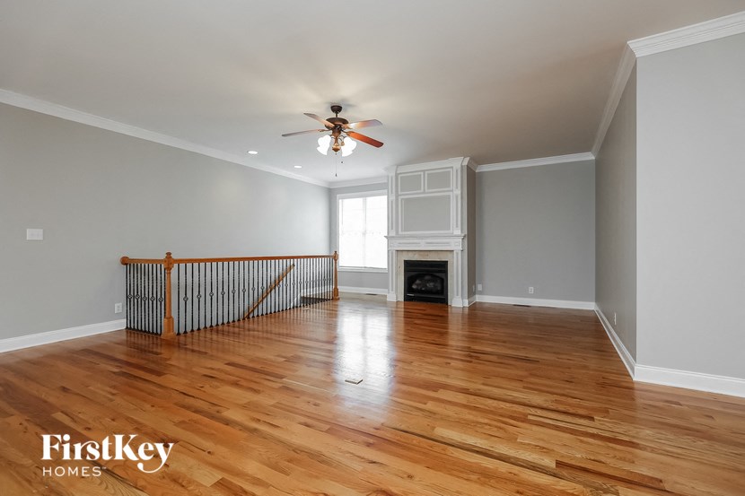 an empty living room with a ceiling fan and a fireplace