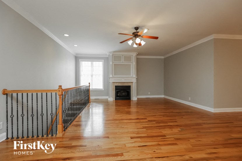 an empty living room with a ceiling fan and a fireplace