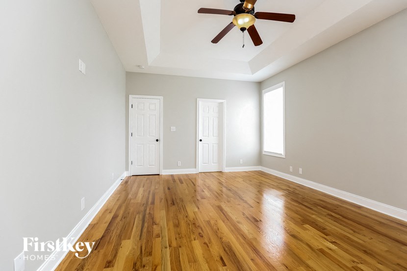an empty living room with wood floors and a ceiling fan