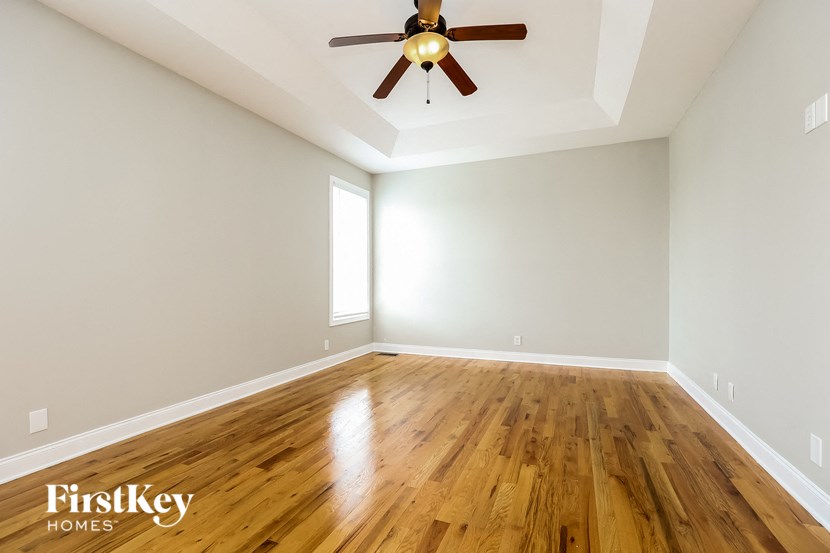 an empty living room with a ceiling fan and wood floors