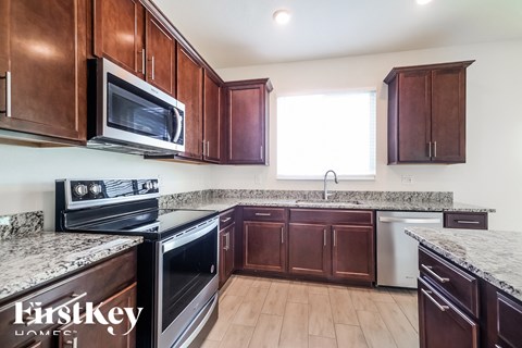a kitchen with wooden cabinets and granite counter tops and a stove and microwave