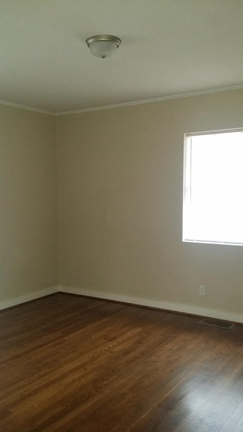 an empty room with wooden floors and a window