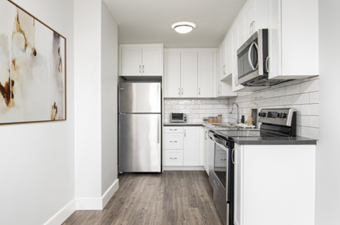 A modern kitchen with white cabinets and stainless steel appliances.