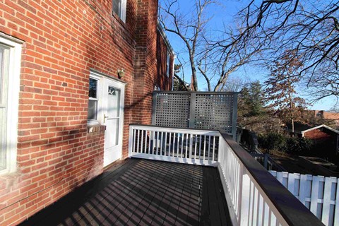 the balcony of a brick house with a white fence