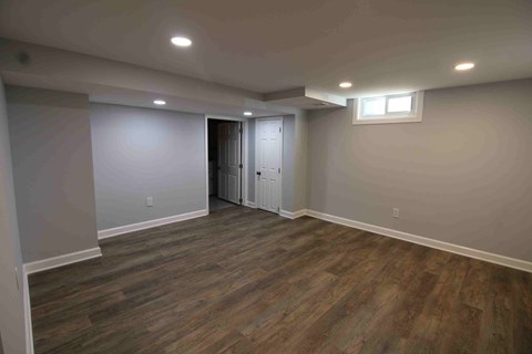 an empty living room with wooden floors and white walls