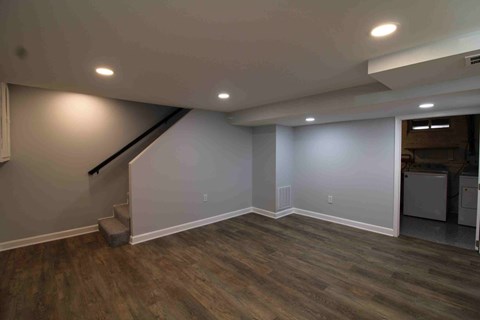 a renovated basement with a hard wood floor and white walls