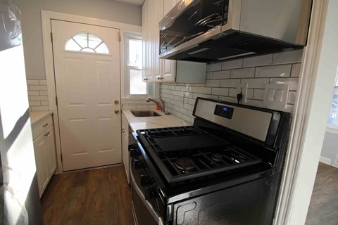 a kitchen with a stove and a sink and a door