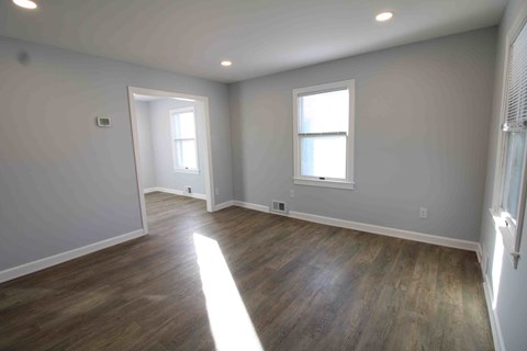 an empty living room with wood floors and a window