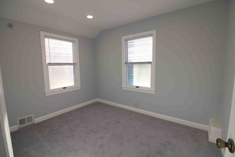 an empty room with two windows and gray walls