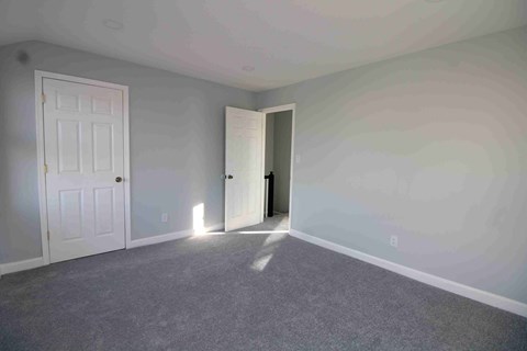 an empty bedroom with a white door and white walls