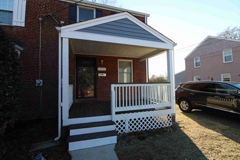a covered porch in front of a brick house