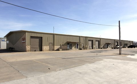 A large industrial building with a parking lot in front.