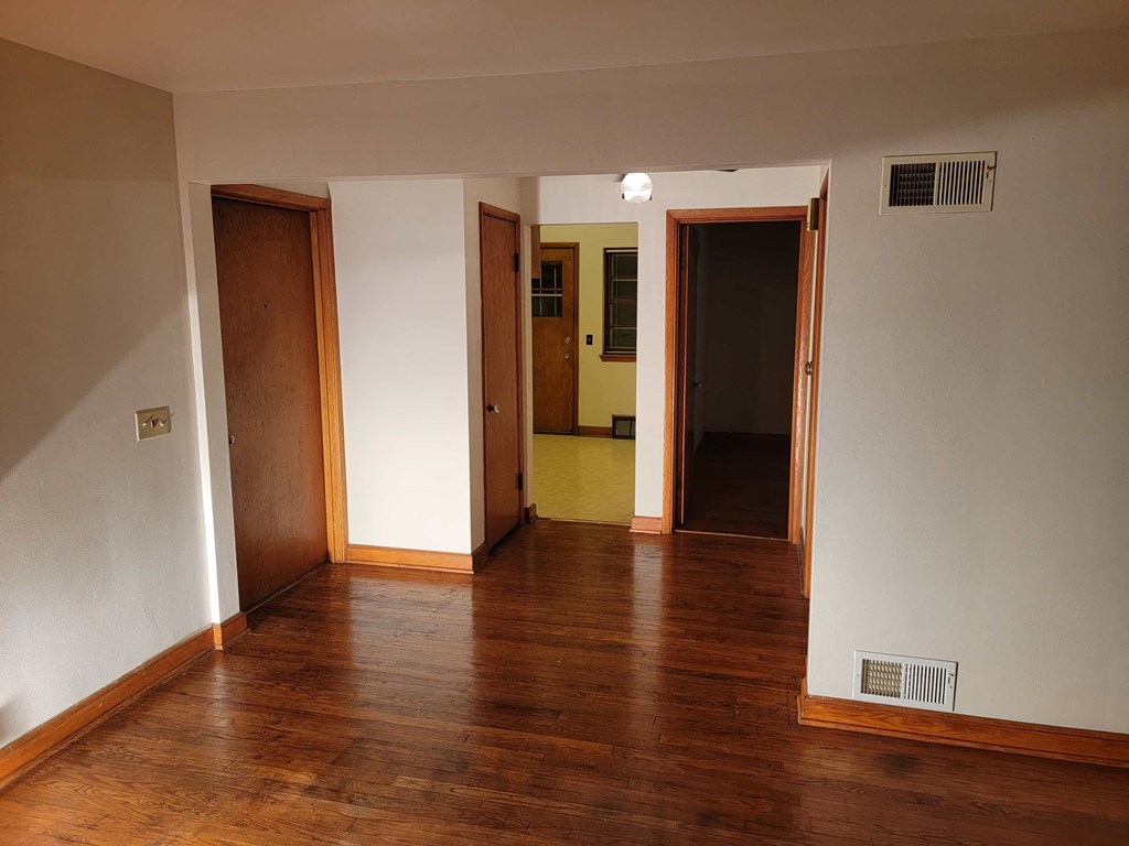 a living room with wood floors and a door to a hallway