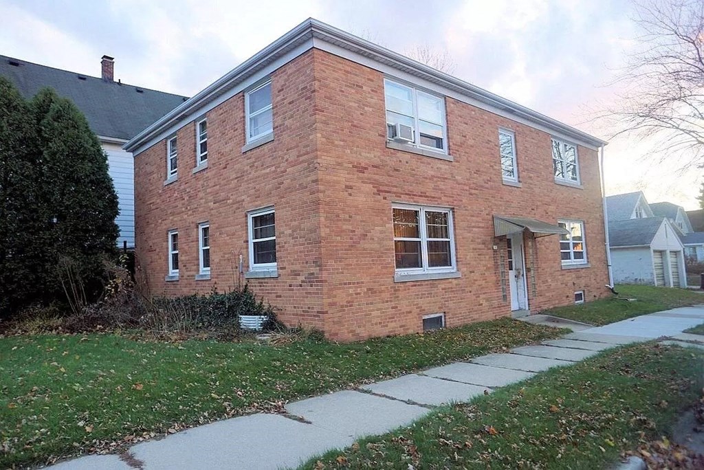 a brick house with a sidewalk in front of it