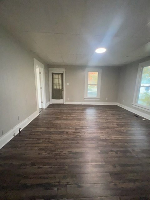 an empty living room with wood floors and a window