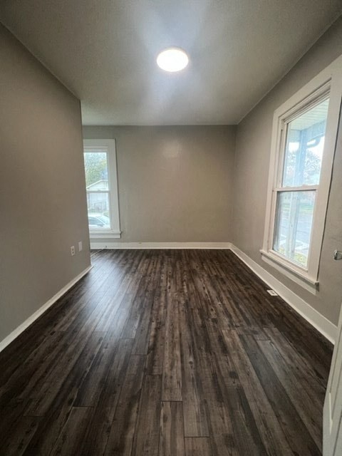 an empty living room with wood floors and a window