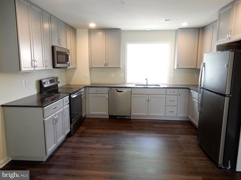 A kitchen with a black fridge and wooden floors.