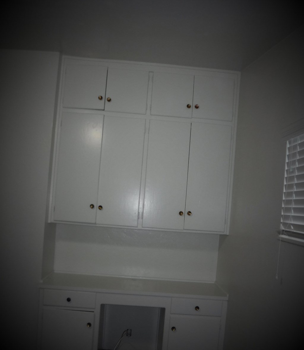 a white kitchen with white cabinets and white window