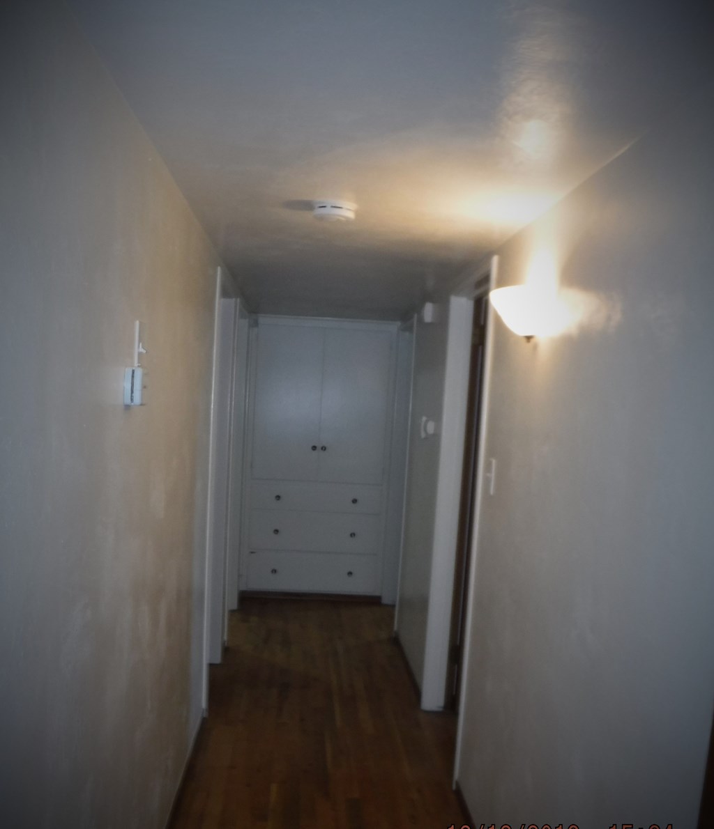 a hallway with white walls and a closet with drawers