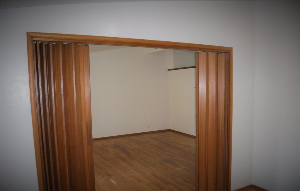 an empty room with a wooden door and a white wall