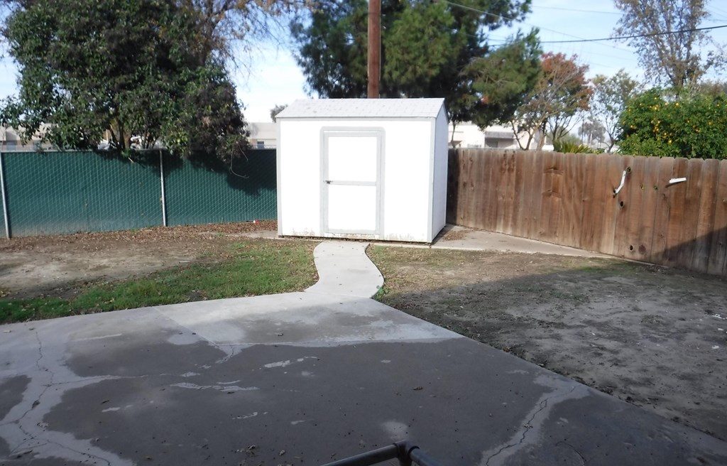 a small white shed in the back yard of a house