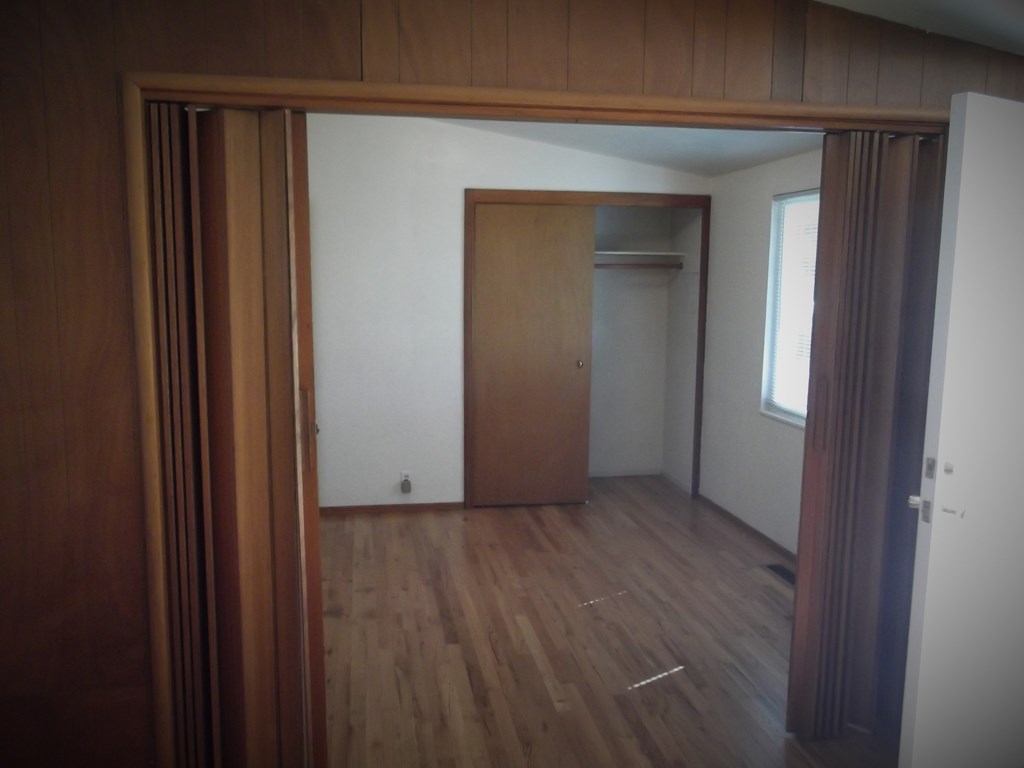 an empty room with wooden floors and a closet