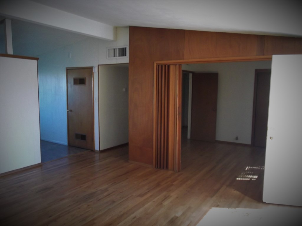 an empty living room with wooden floors and a wooden door