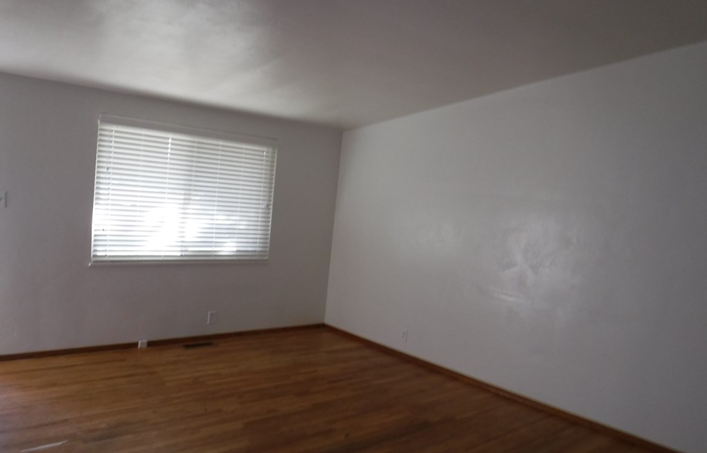 an empty room with wooden floors and a window