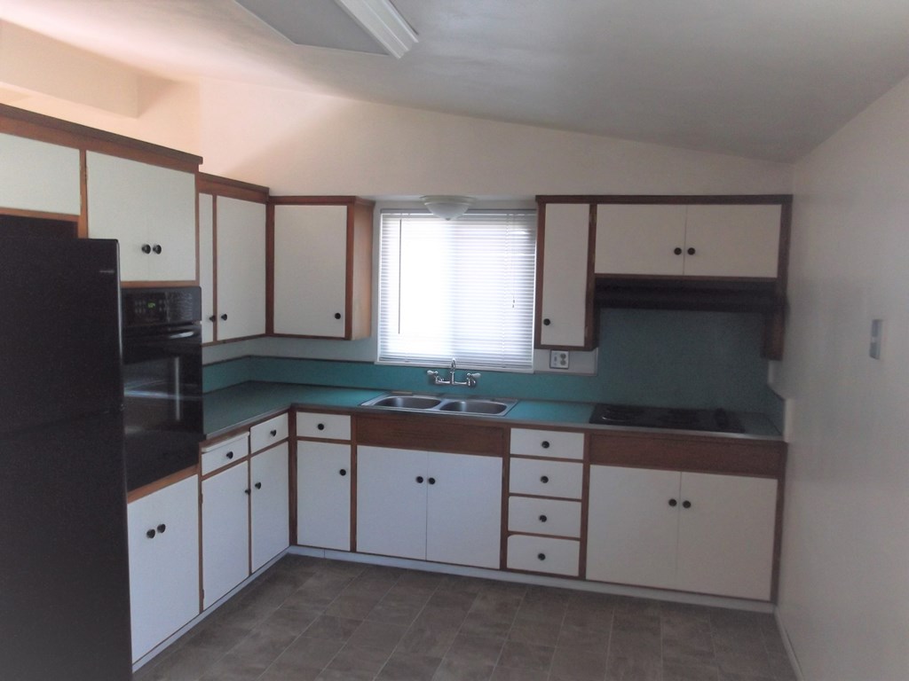 an empty kitchen with white cabinets and a green counter top