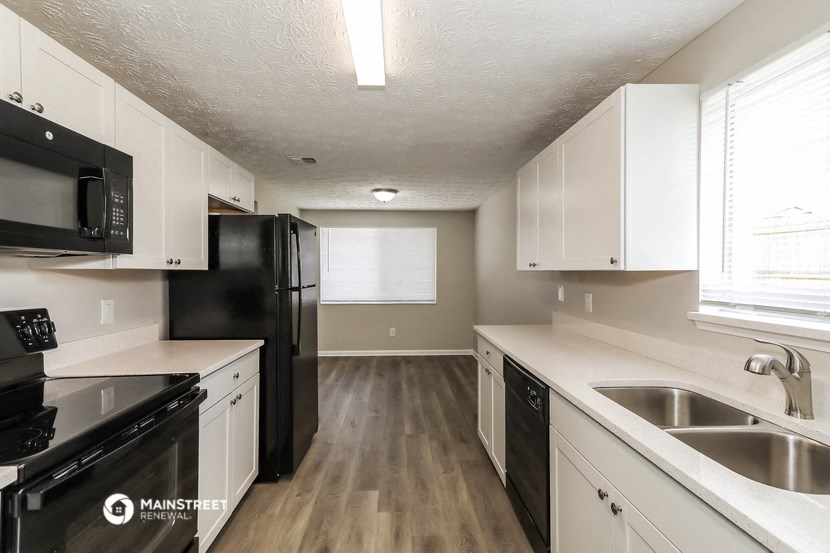 an empty kitchen with white cabinets and black appliances
