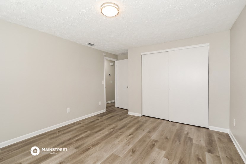 the spacious living room of an apartment with white walls and wood flooring