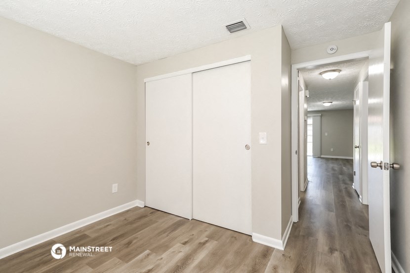 the living room and hallway of an apartment with white walls and wood flooring