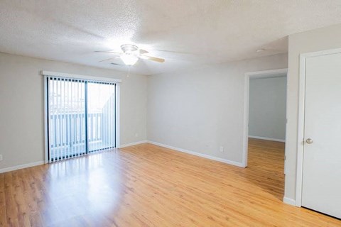 A room with a sliding glass door and a ceiling fan.
