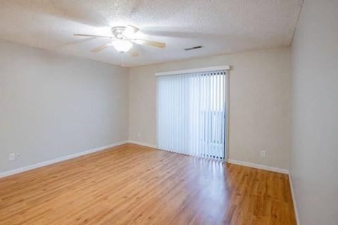 A room with a ceiling fan and wooden flooring.