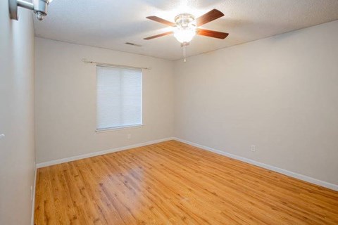 A room with a ceiling fan and wooden flooring.