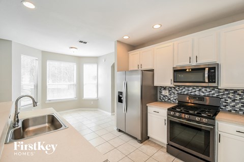 A kitchen with a stove, sink, refrigerator, and microwave.