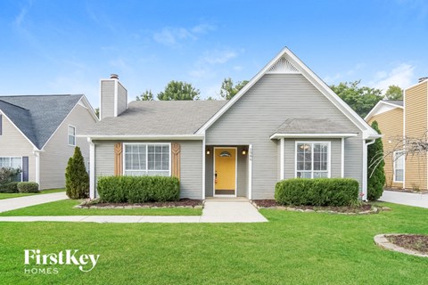 a white house with a green lawn and a yellow door